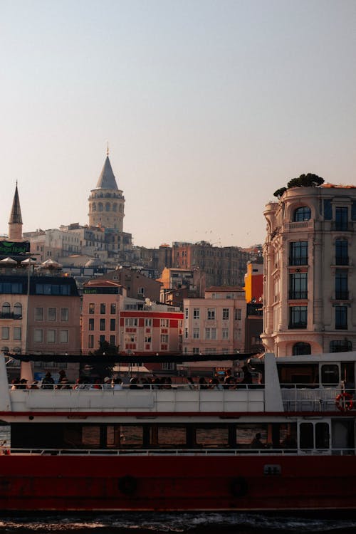 A boat is traveling down the water in front of a city