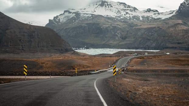 Picturesque road through Vík í Mýrdal with stunning mountain backdrop, ideal for adventure travel.