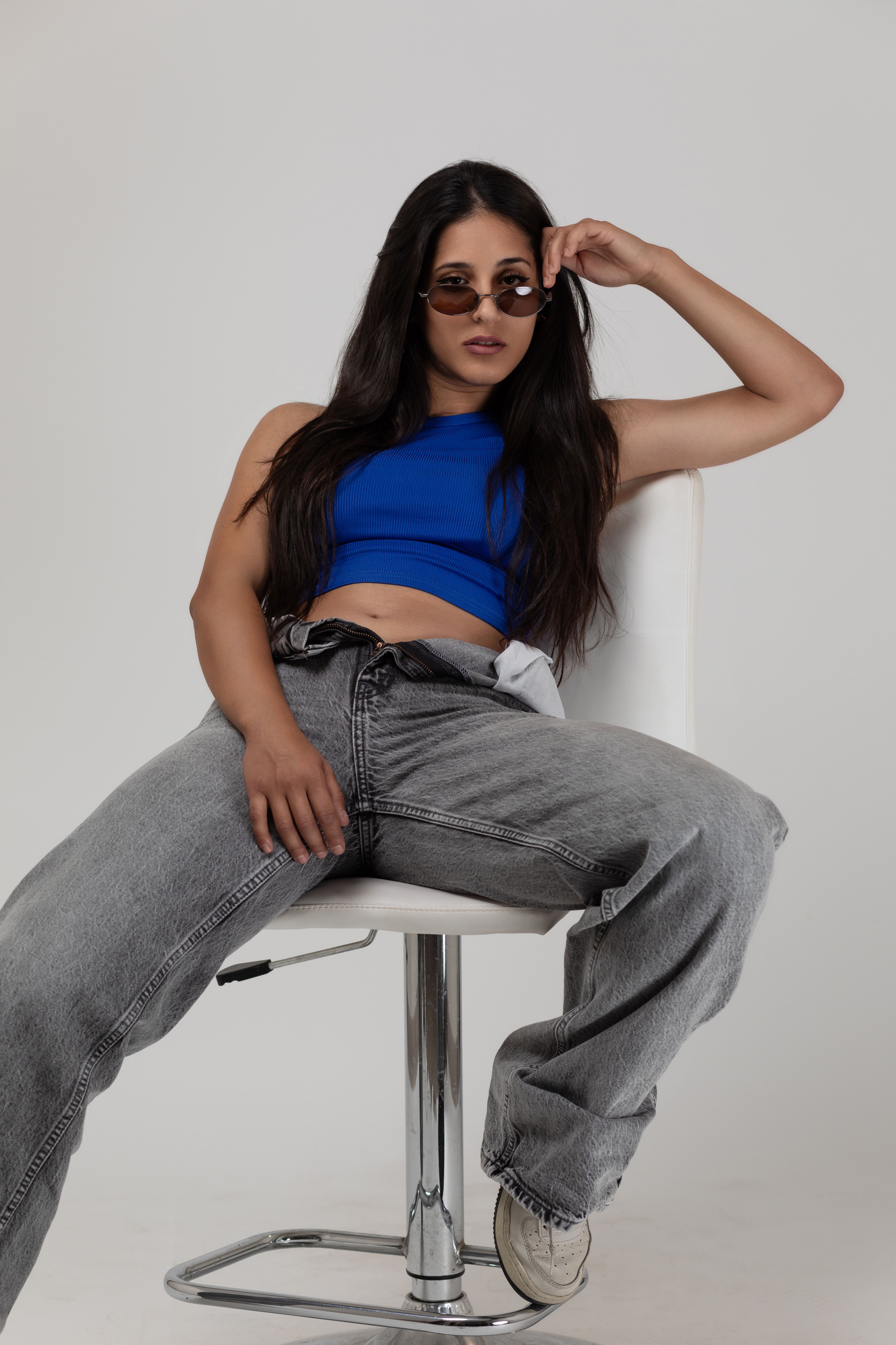 A woman in jeans and a blue top sitting on a chair · Free Stock Photo