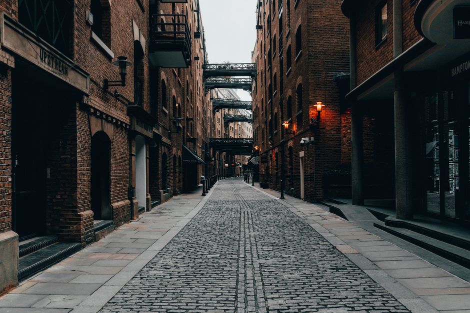 Cobblestone alleyway in London's atmospheric downtown, enclosed by brick buildings.