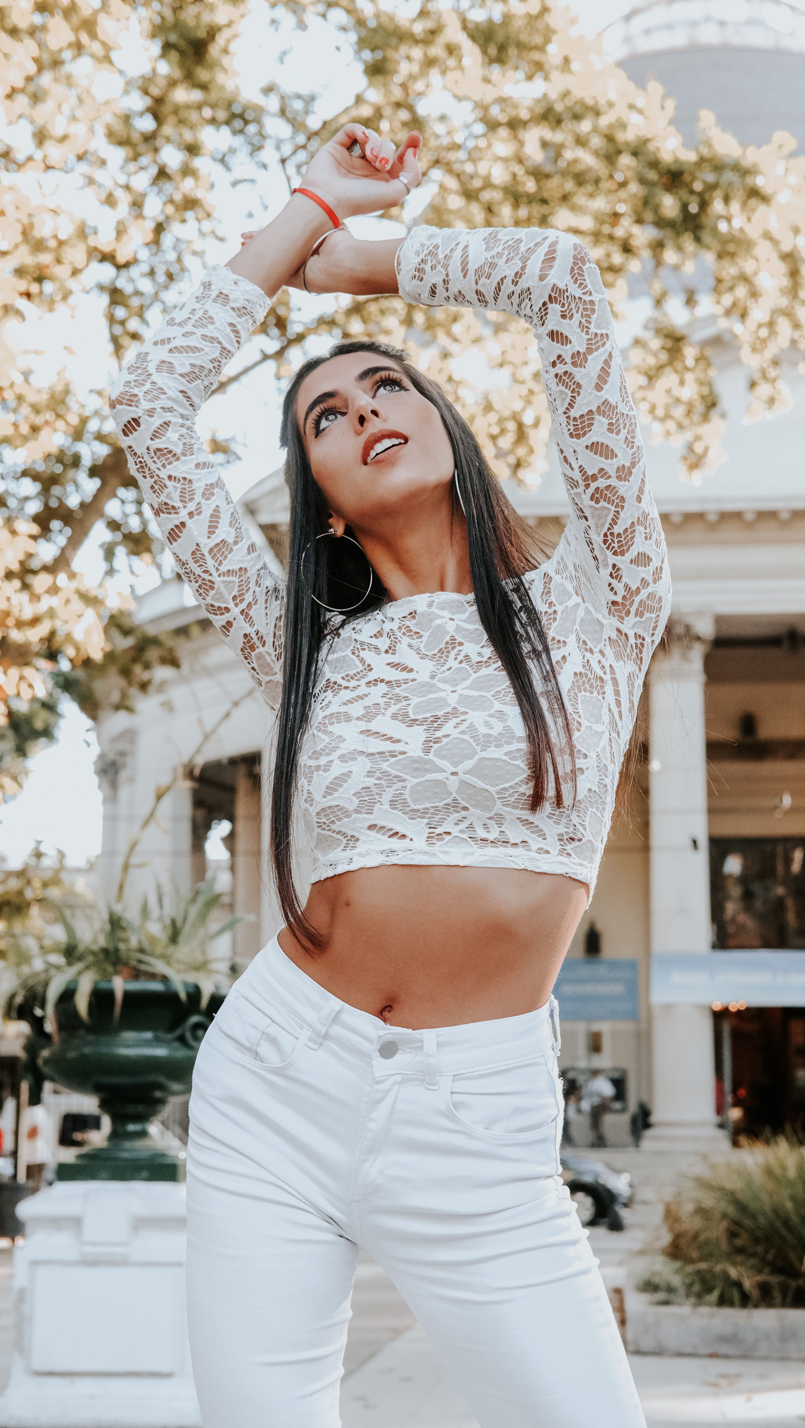 Stylish woman modeling in white lace top and pants in Buenos Aires setting.