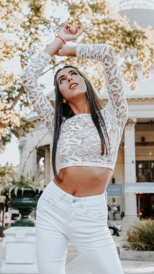 Free Stylish woman modeling in white lace top and pants in Buenos Aires setting. Stock Photo
