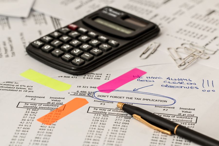 A printed financial statement marked up with a highlighter beside a calculator
