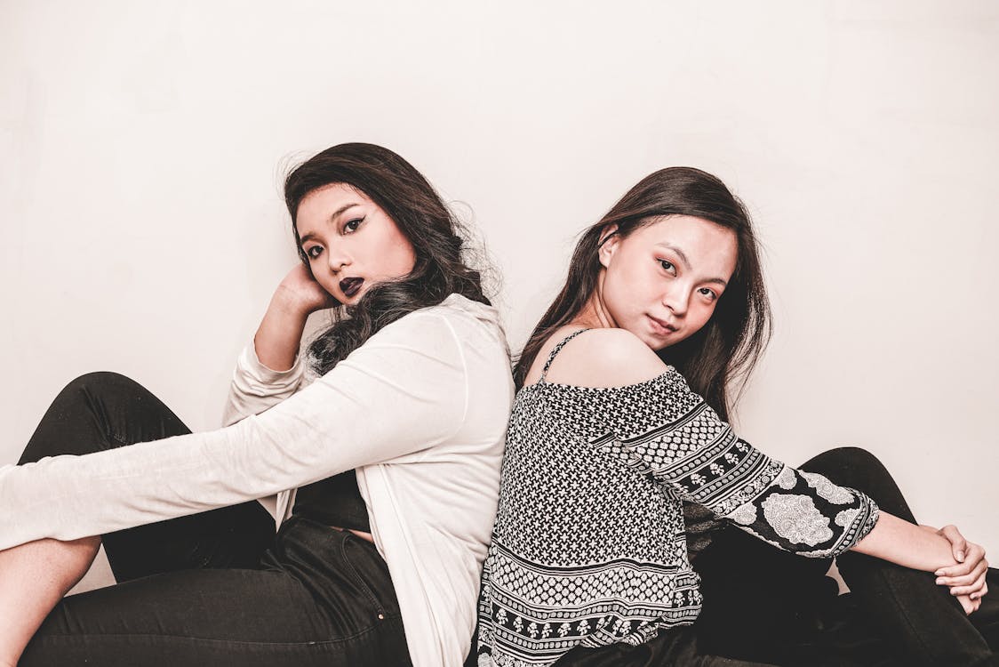 Free Photograph of two women sitting while leaning on each other back to back Stock Photo