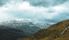 挪威白雪皑皑的山脉和连绵起伏的丘陵，在戏剧性的云层下显得格外壮丽