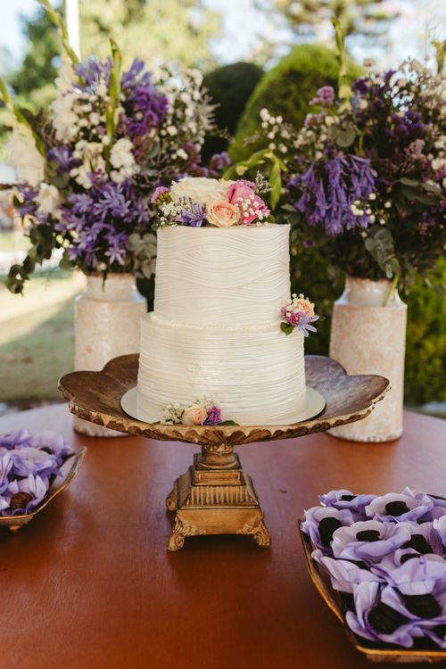 Free Two-tier white wedding cake with floral decor in outdoor garden setting. Stock Photo