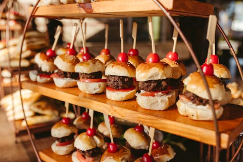 A wooden stand with mini burgers and cherry sticks