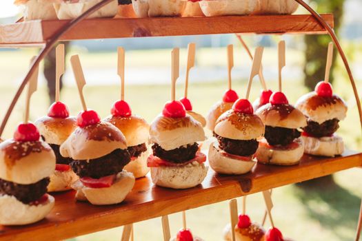 Close-up of mini burgers with cherries on skewers; perfect for catering and events.