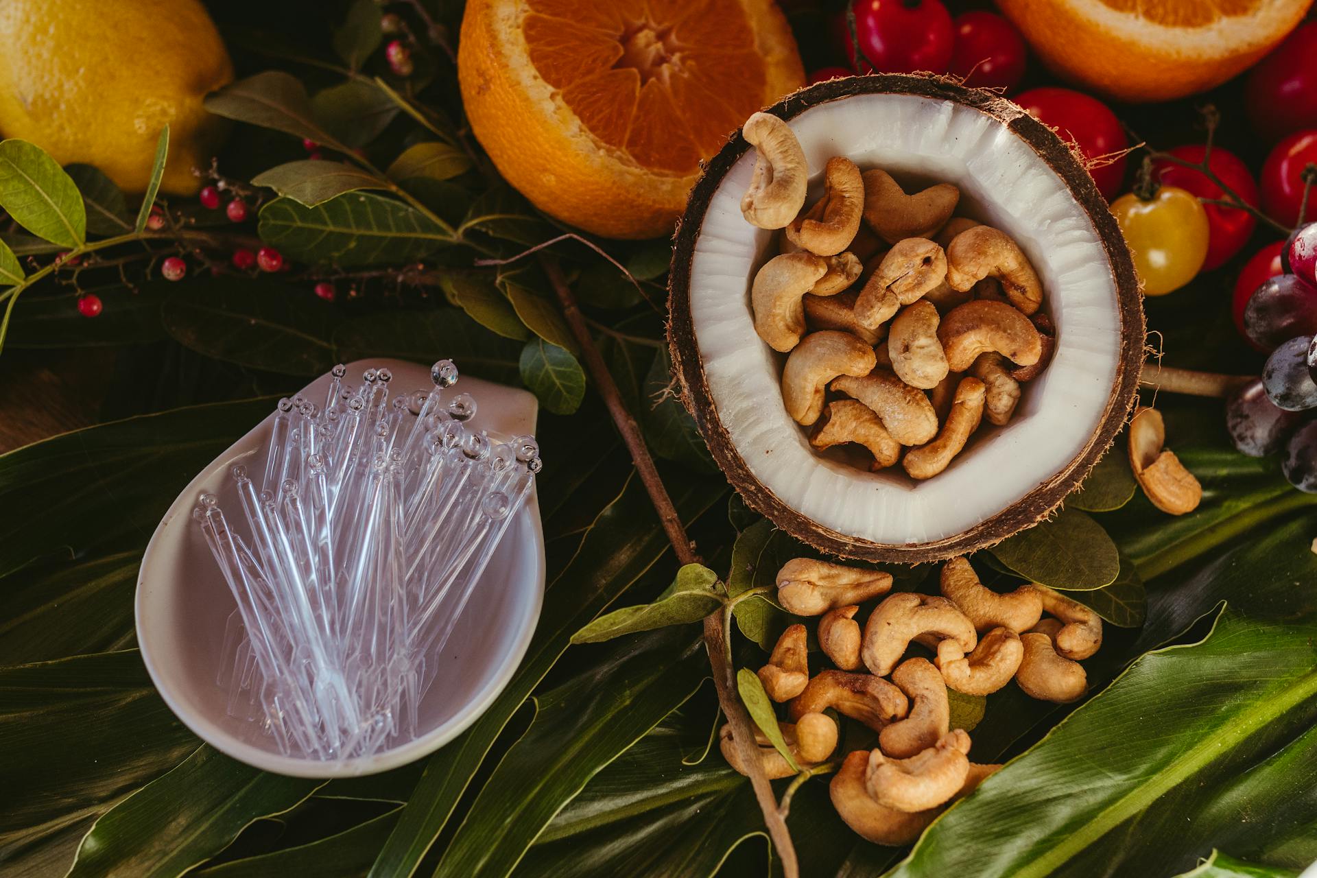 Vibrant flat lay of cashew nuts, tropical fruits, and leaves. Perfect for food photography.