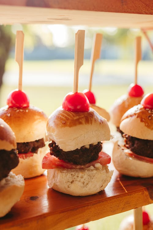 A tray of mini burgers with cherry sticks