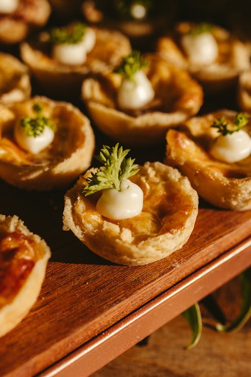 Small pies with cheese and herbs on top of a wooden tray