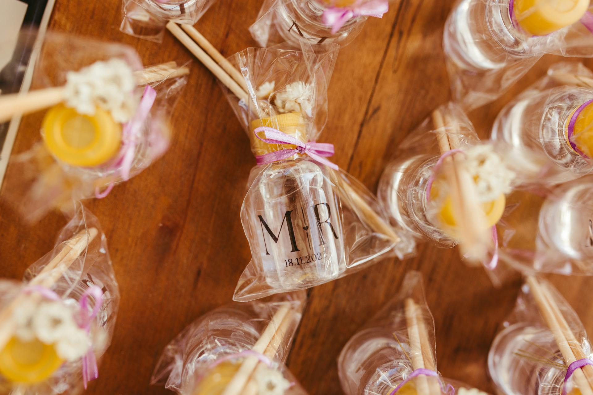 Aesthetic display of wedding favor bottles wrapped in transparent foil with aromatic sticks.