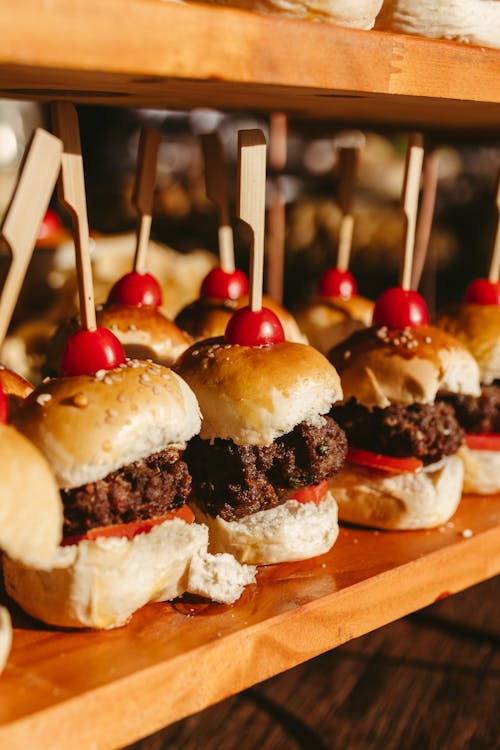 A tray of mini burgers with cherry tomatoes
