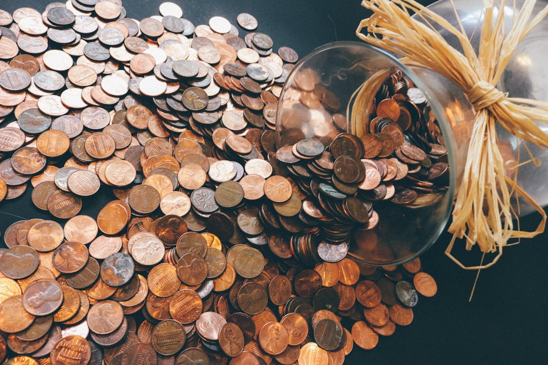 A jar of copper coloured coins which have spilled. 