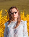 一位年轻女子戴着墨镜，站在一片黄色的花朵中