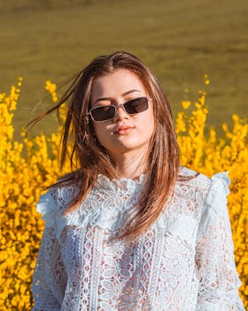 一位年轻女子戴着墨镜，站在一片黄色的花朵中