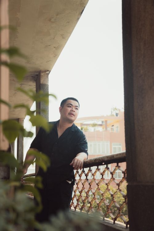 Free A thoughtful adult Asian man standing on a balcony in Ho Chi Minh City, Vietnam. Stock Photo