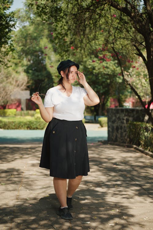 A woman in a skirt and hat walking on a path