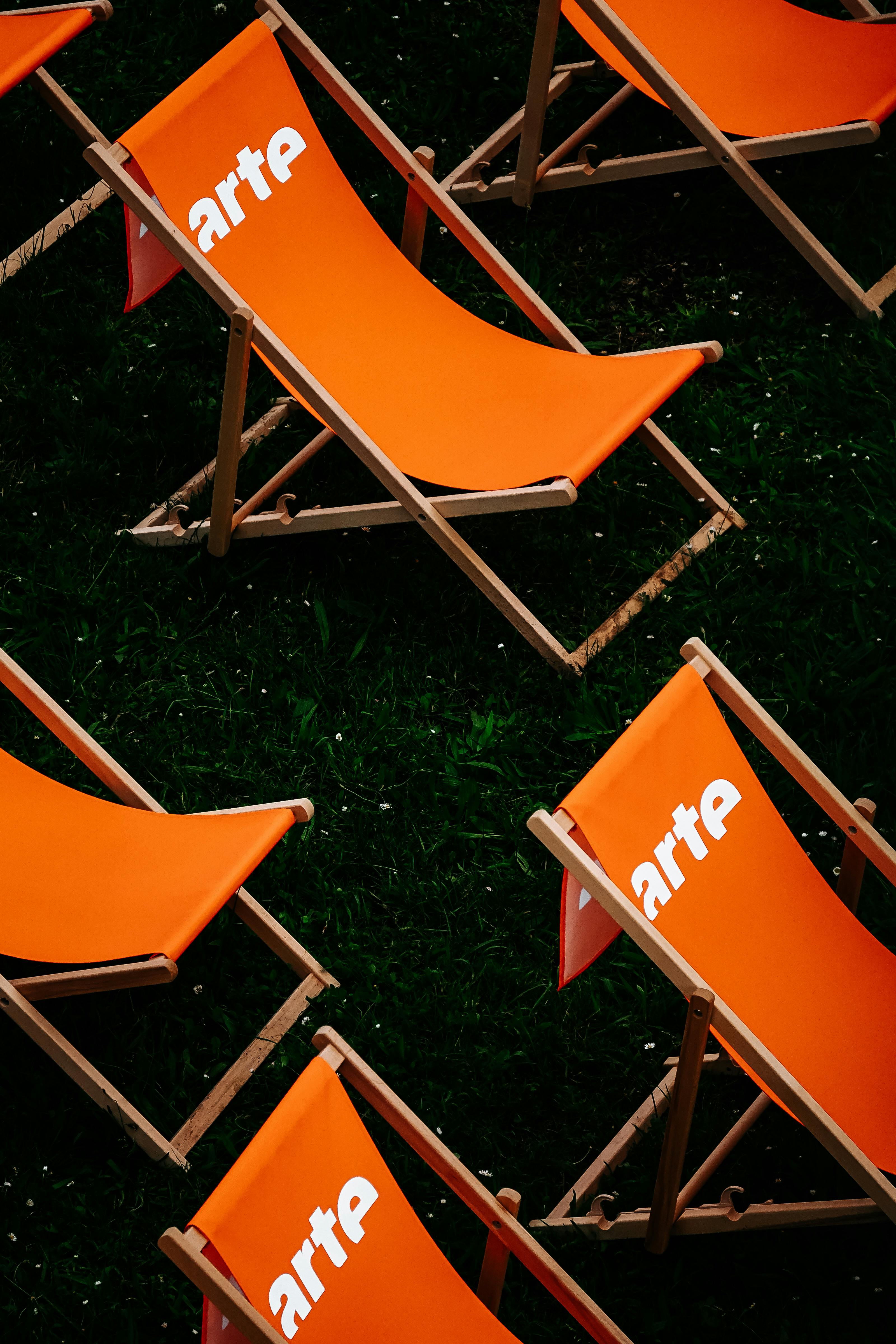 Free High angle view of orange sunbeds on green grass, creating a contrasting and vibrant outdoor scene. Stock Photo