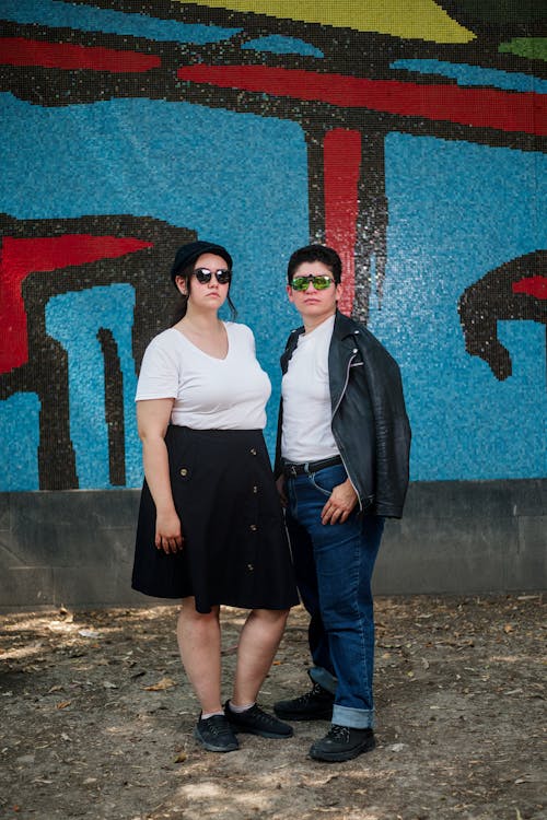 Two people standing in front of a graffiti wall