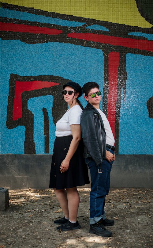 Two people standing in front of a graffiti wall