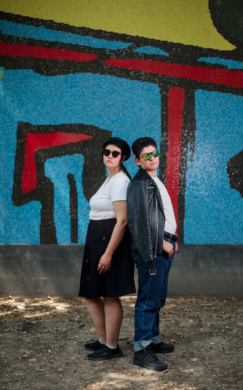 Two people standing in front of a graffiti wall