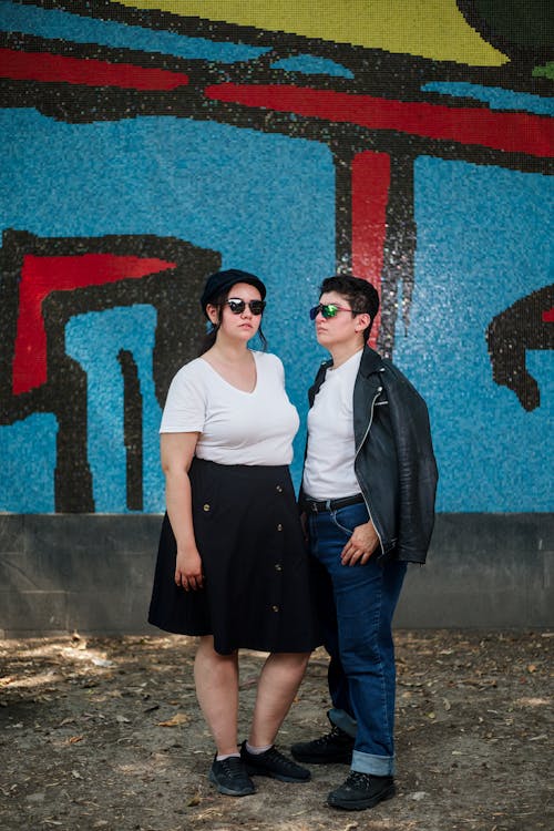 Two people standing in front of a colorful wall