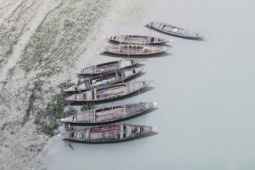 Free Aerial perspective of traditional wooden boats moored along a calm sandy shore. Stock Photo