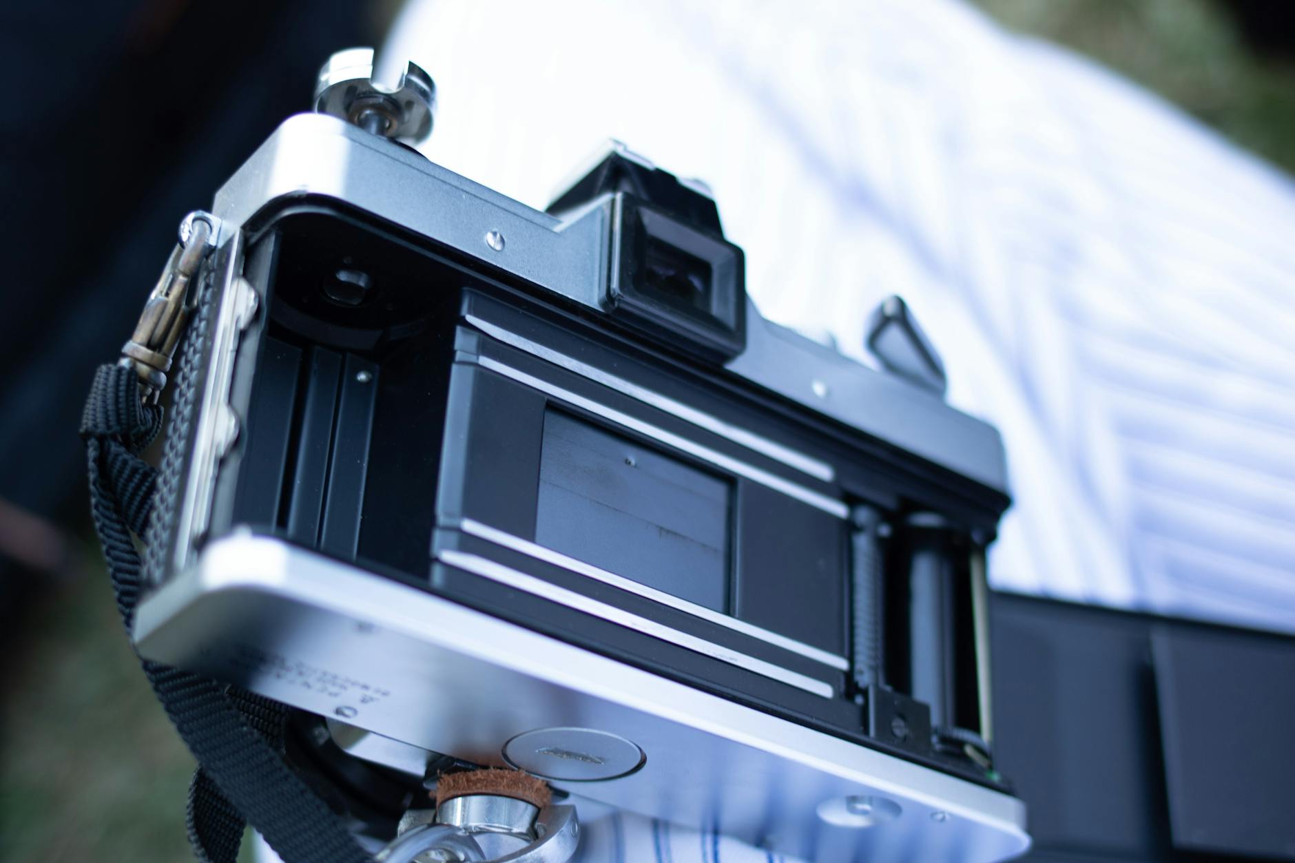 A detailed look at an open vintage camera showing the film compartment and strap.