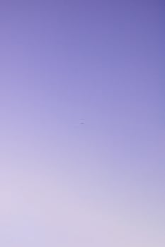 一架飞机在晴朗的暮色天空下飞行，捕捉着极简主义的空中之美