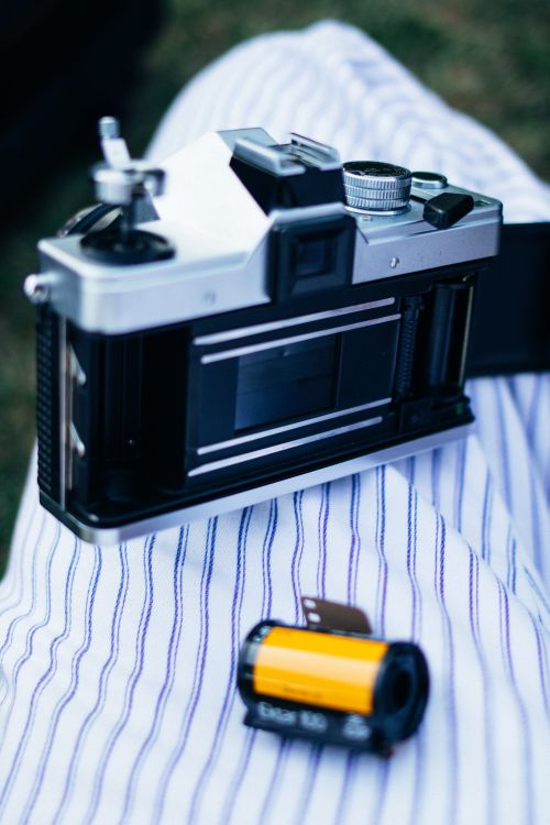 Free A detailed view of a vintage camera with an open back and a film roll on a striped fabric surface. Stock Photo