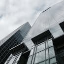 两座现代摩天大楼的玻璃外墙映衬着多云的天空，从低角度看去