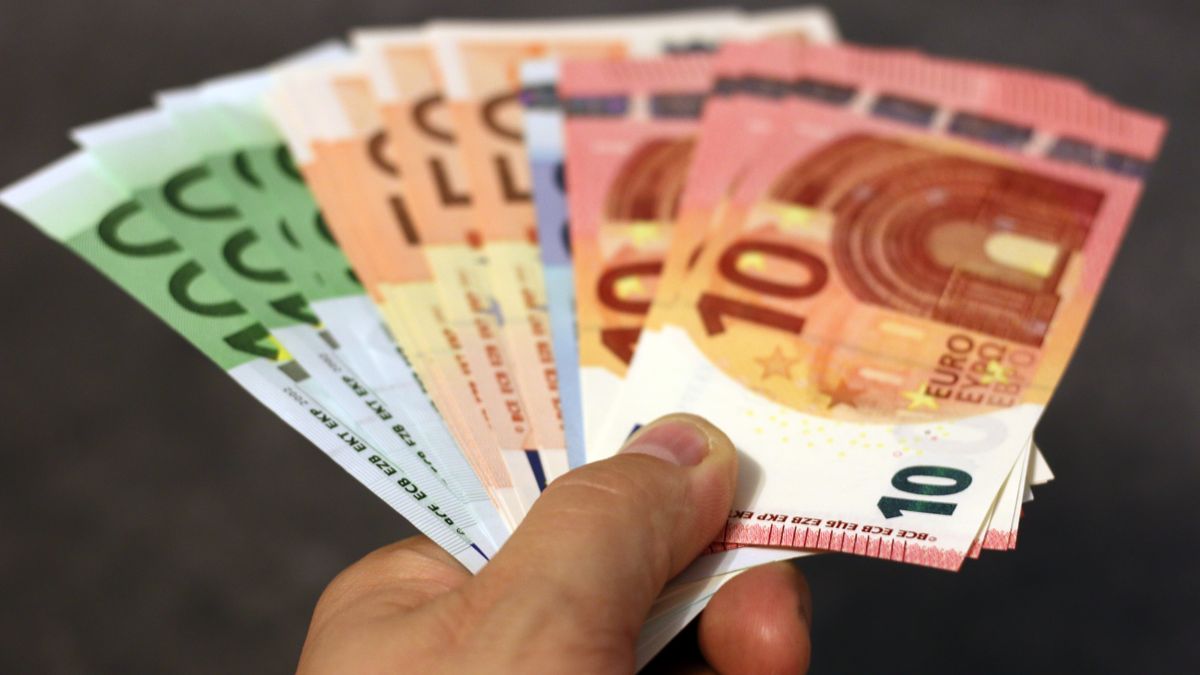 A fan of euro banknotes in various denominations held in a hand.