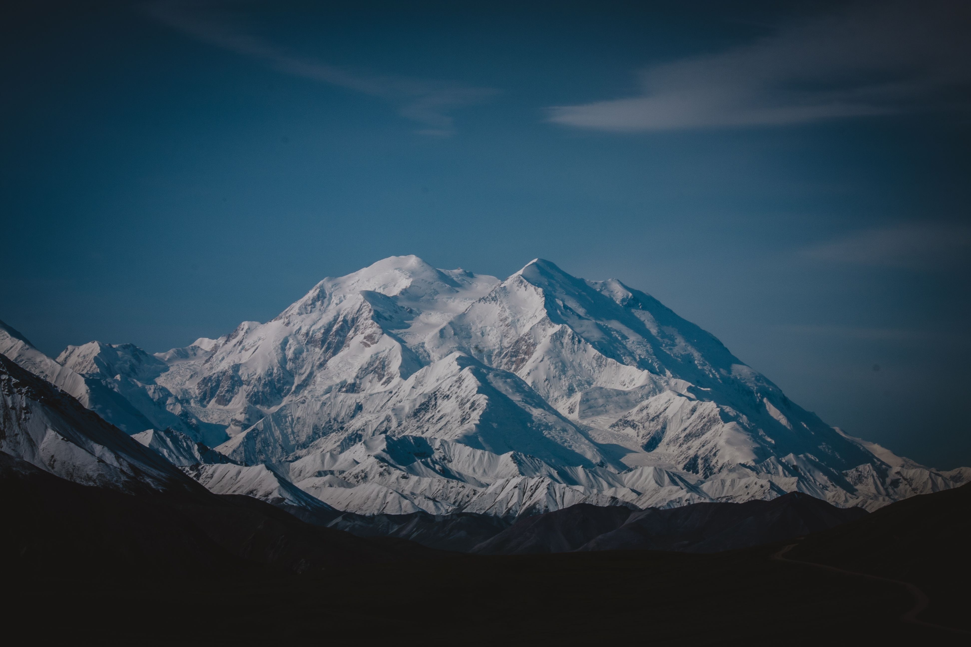 Breathtaking view of Denali mountain peak covered in snow under a dramatic sky.
