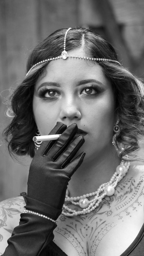 Free Vintage portrait of a woman in elegant attire with cigarette, evoking a retro vibe. Stock Photo