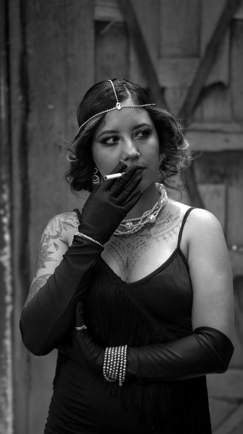 Free Vintage-inspired black and white portrait of a woman in elegant attire with jewelry and a cigarette. Stock Photo