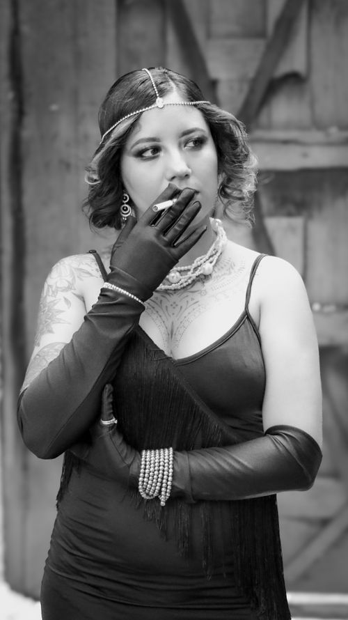 Free Black and white portrait of an elegant woman in vintage attire smoking indoors. Stock Photo