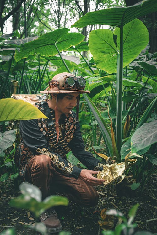 A man in a hat and hat sitting in the jungle