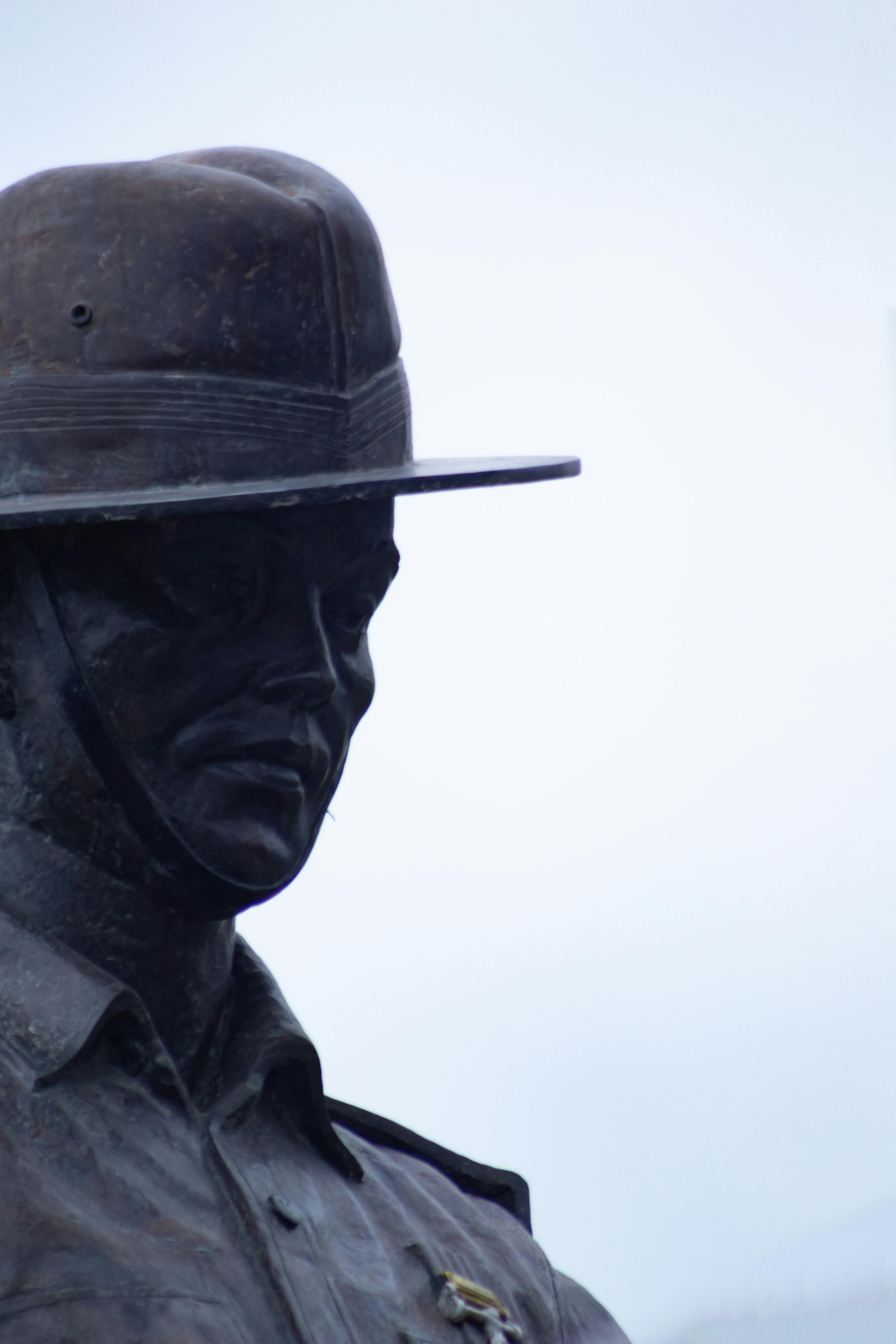 Close-up of a bronze soldier statue outdoors under a clear sky.