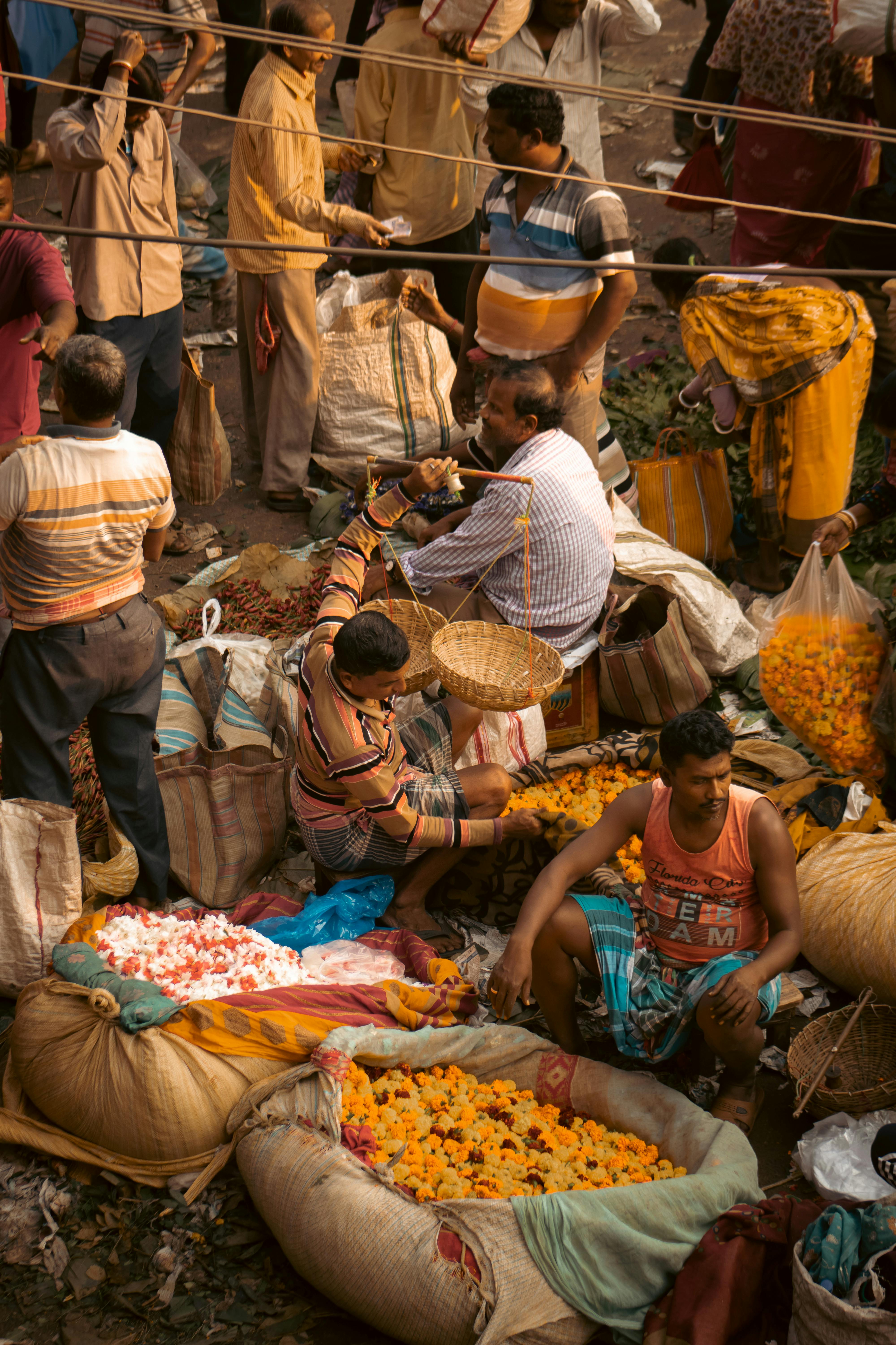 aerial view of people sitting and walking among the bags filled with flowers