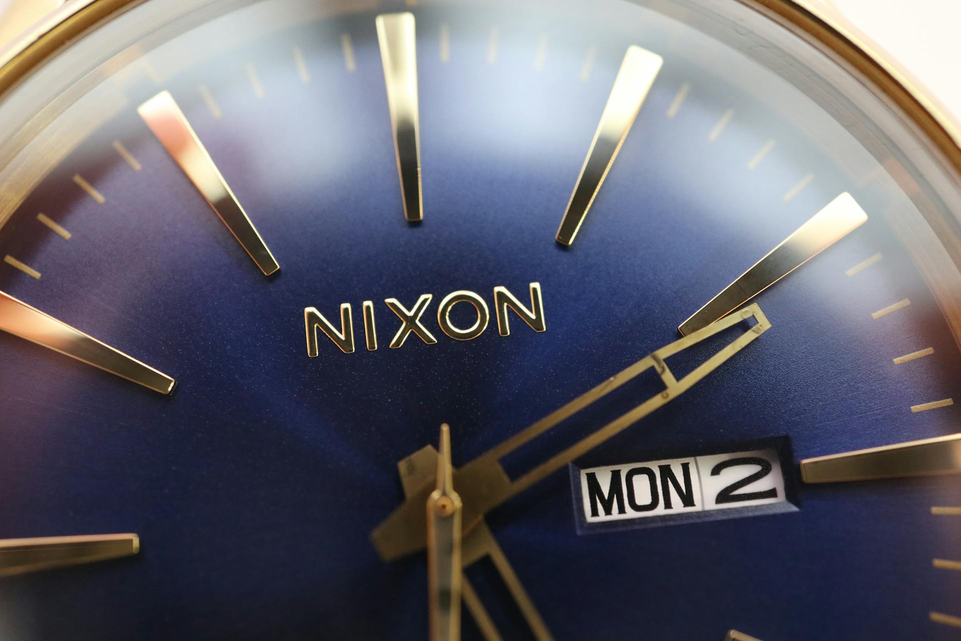 Detailed close-up of a Nixon watch dial showcasing time and date with a sleek blue face.