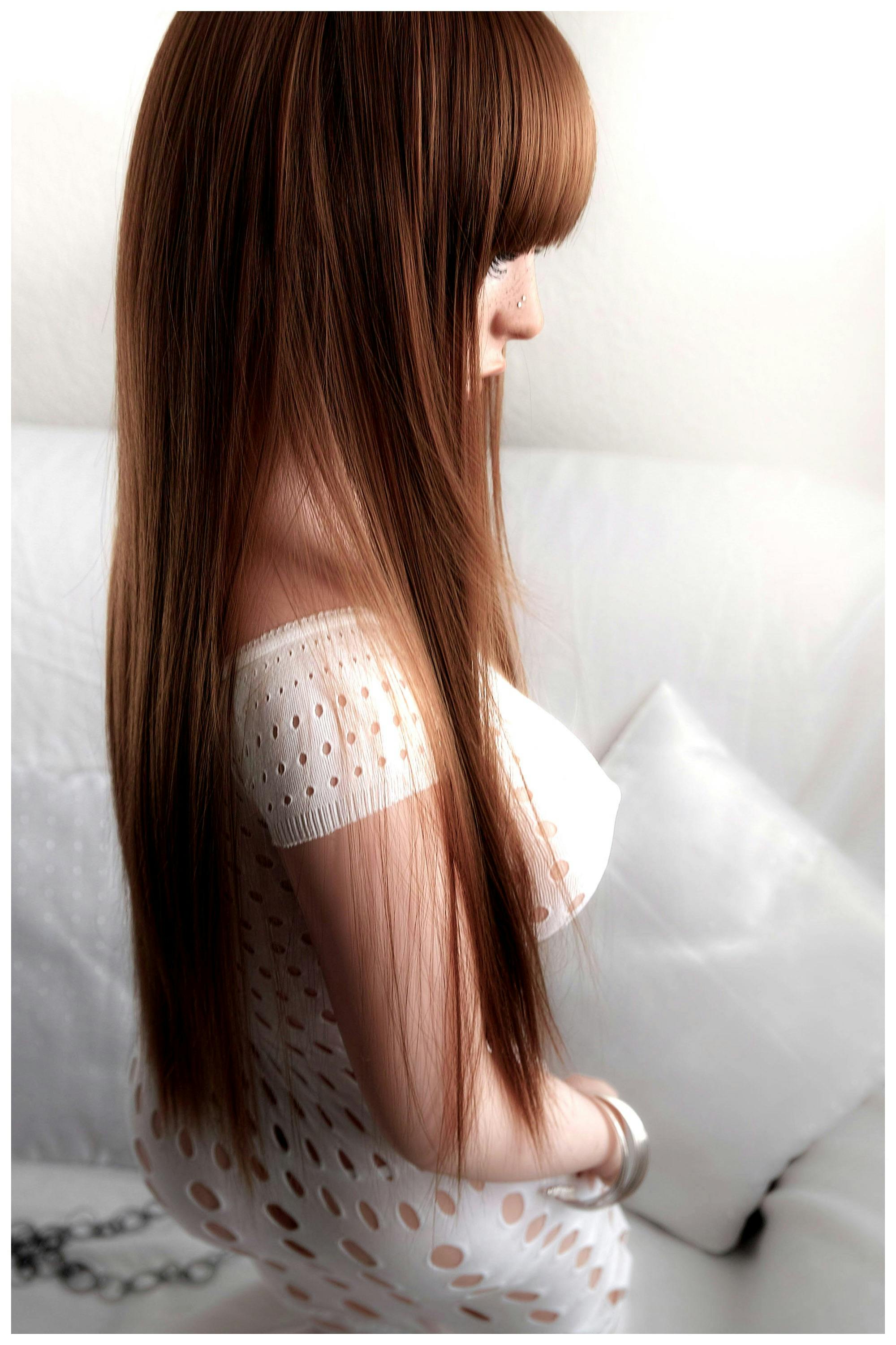 Profile view of a woman with long hair in a white lace dress on a white couch.