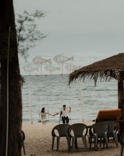 Free A couple holding hands on swings by the beach in Phu Quoc, Vietnam, under a cloudy sky. Stock Photo