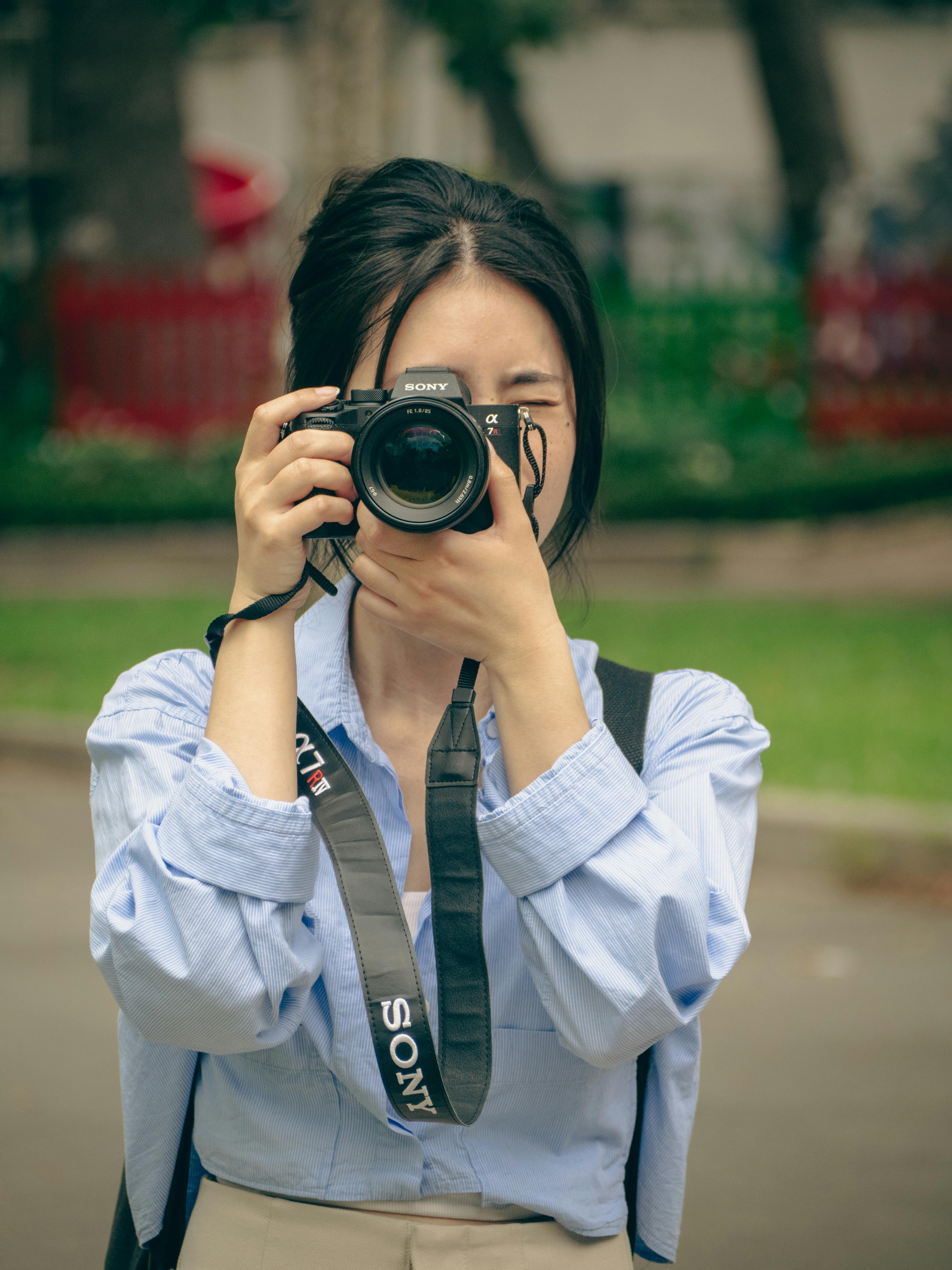 Woman in blue shirt taking photos in Ho Chi Minh City park. Vibrant and engaging setting.
