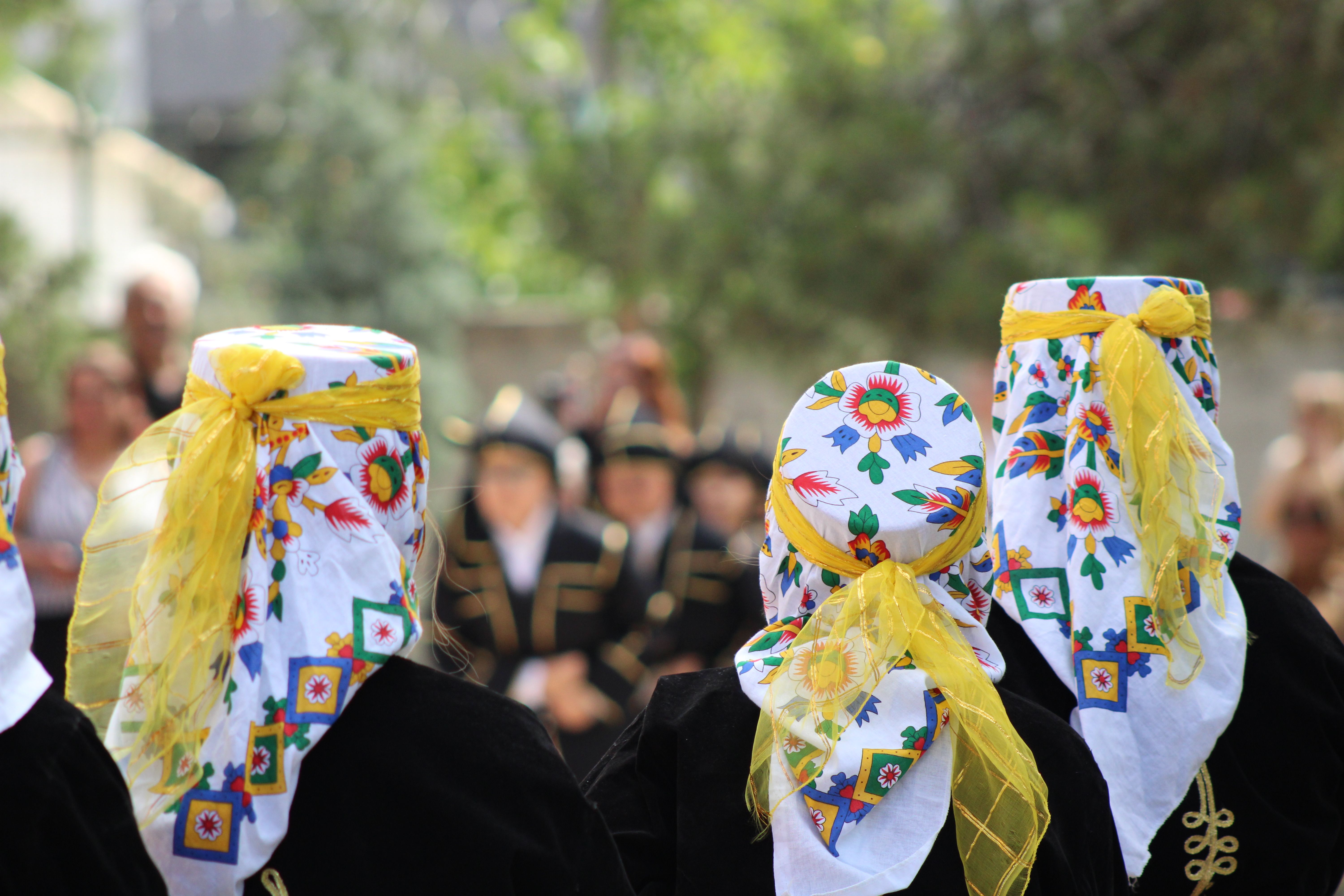 Women in floral patterned headscarves at a traditional outdoor celebration.