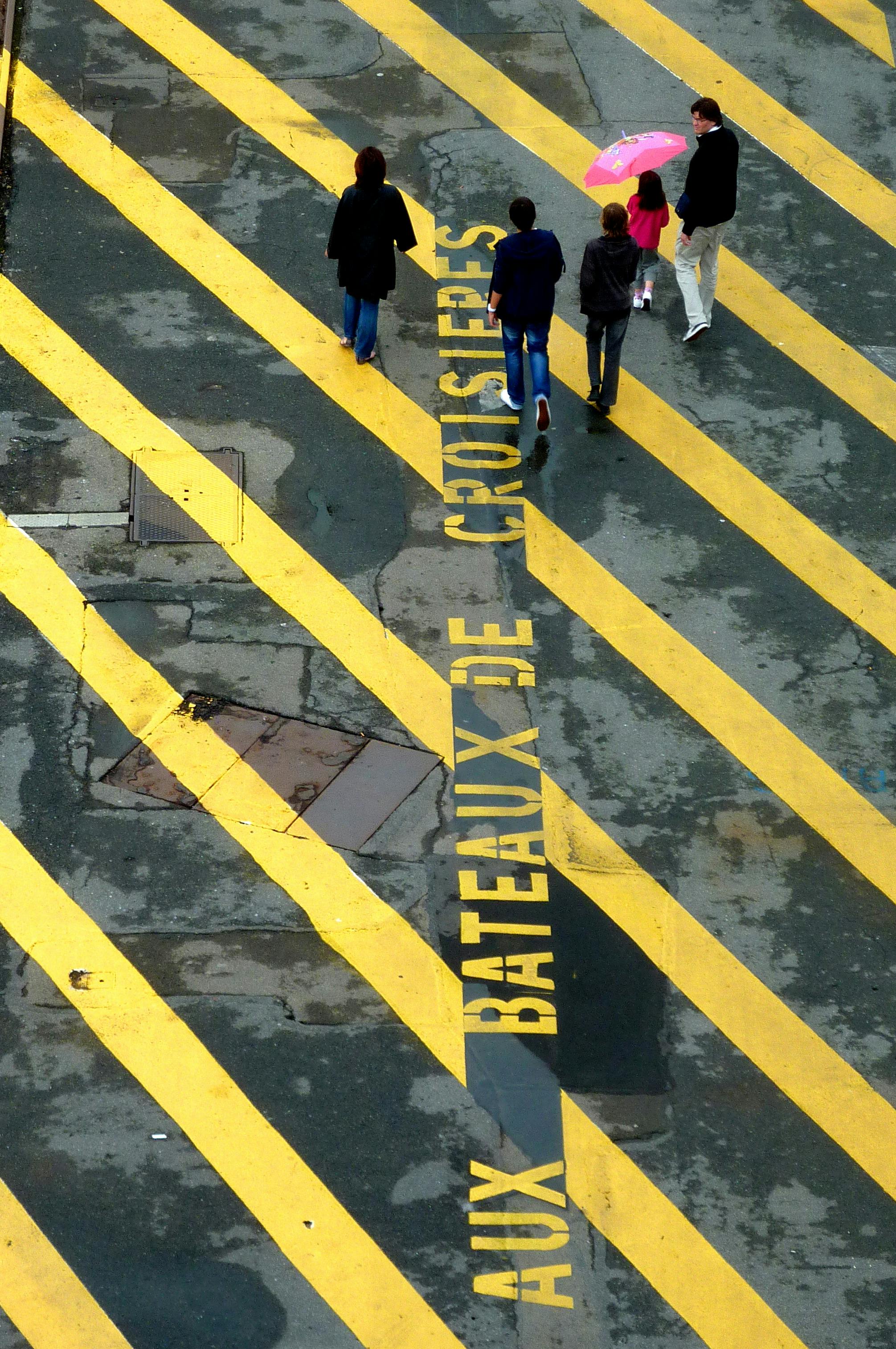Aerial view of people walking on a marked street with vivid yellow stripes.