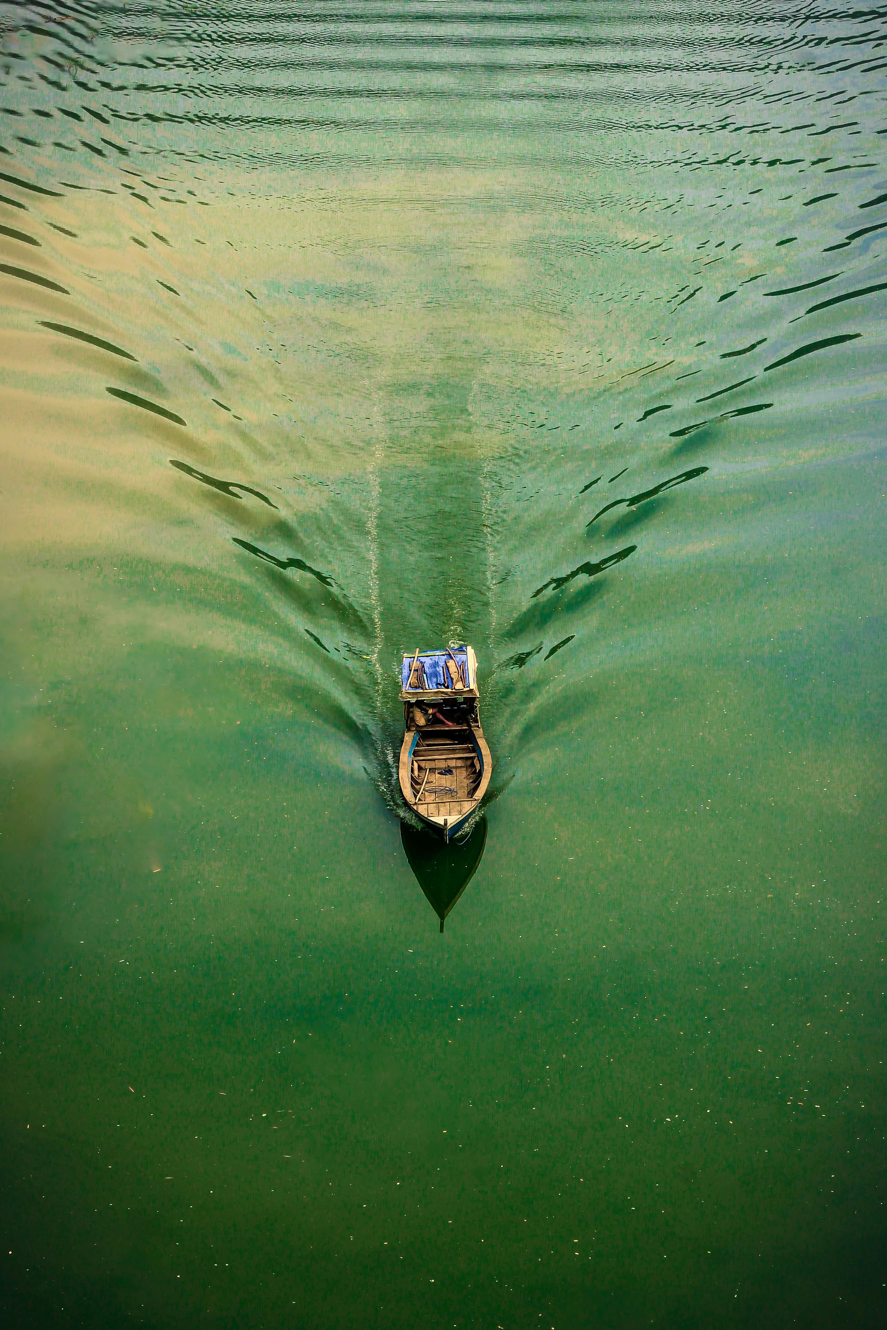 A solitary boat sails across the tranquil green waters of West Java, Indonesia, in an aerial view.