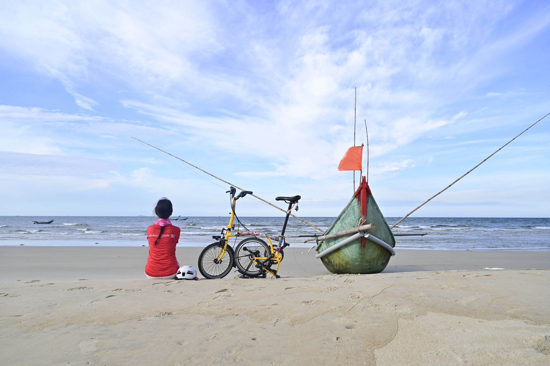 A serene scene at Tam Kỳ Beach, Vietnam, featuring a resting woman next to a bicycle and boat.