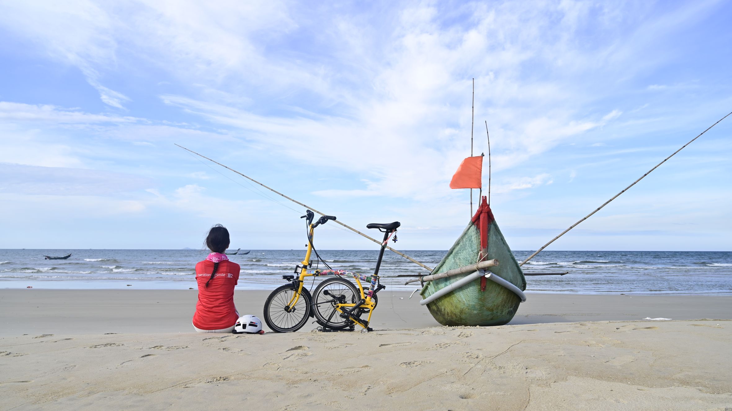 A serene scene at Tam Kỳ Beach, Vietnam, featuring a resting woman next to a bicycle and boat.