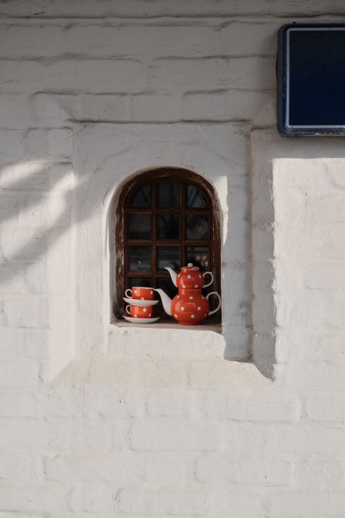 Free Orange polka dot teapot and cups in a rustic window sill on a sunny day. Stock Photo